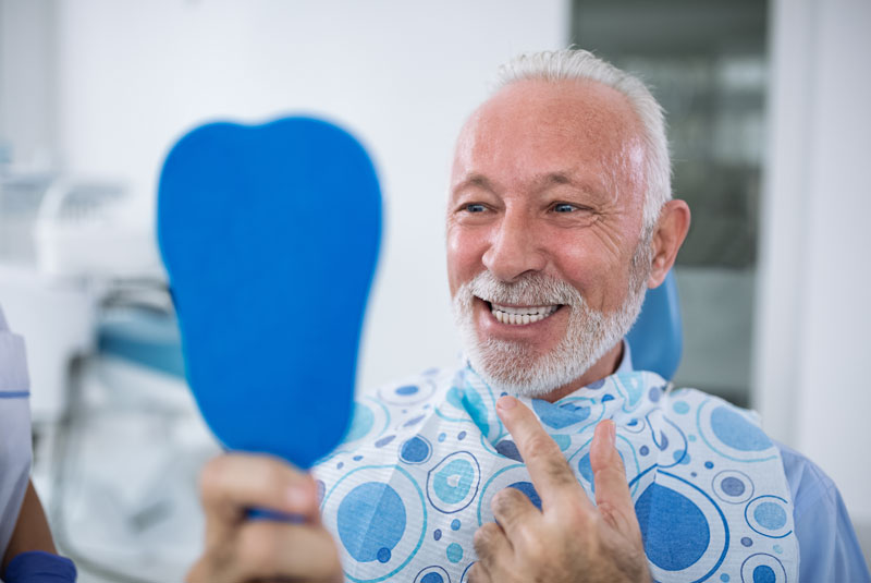 An image of an older man smiling at the dentist.
